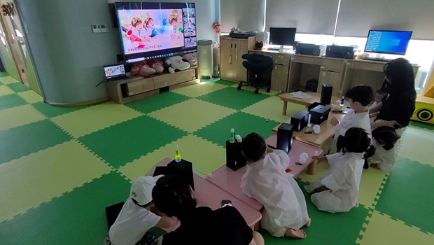공립영흥어린이집 원아들이 온라인 수업에서 손전등으로 직접 만든 1차시 &lsquo;깜깜상자&rsquo; 속을 들여다보고 있다.
